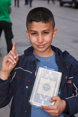 Berlin  Deutschland  Junge Karim  10 Jahre alt  zeigt mit erhobenem Zeigefinger den Koran