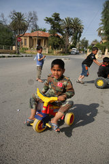Nikosia  Tuerkische Republik Nordzypern  ein Junge in Militaerkleidung auf einem Dreirad mit seinen Freunden
