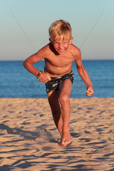 Santa Margherita di Pula  Italien  Junge am Strand rennt wuetend auf den Betrachter zu