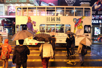 Hong Kong  China  Menschen ueberqueren bei Regen eine Strasse