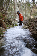 Jerzens  Oesterreich  ein Junge steht auf einem gefrorenen Bachlauf