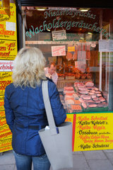 Muenchen  Deutschland  eine Frau guckt in die Auslage eines Fleischers
