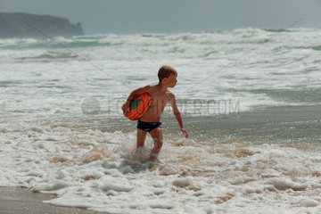 Santa Margherita di Pula  Italien  Junge laeuft mit Schwimmbrett am Strand entlang