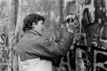 Berlin  Deutschland  ein junger Mann schlaegt Teile aus der Mauer