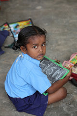 Vijayawada  Indien  eine kleine Schuelerin mit ihrer Tafel beim Unterricht