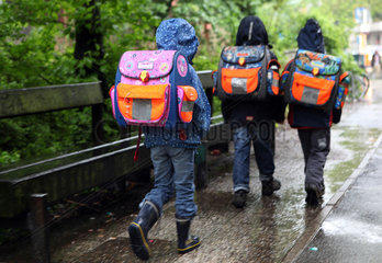 Berlin  Deutschland  Kinder bei Regenwetter auf dem Weg zur Schule