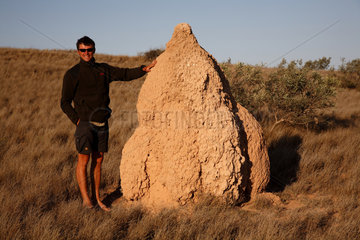 Canarvon  Australien  ein junger Mann neben einem Termitenhuegel