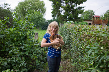 Grammendorf  Deutschland  ein Maedchen mit einem Huhn im Arm
