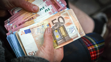 Mann haelt Euro Geldscheine in den Haenden