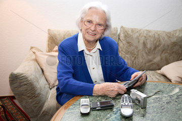 Berlin  Deutschland  alte Frau mit Handys  Digitalkamera und einer Nintendo Konsole