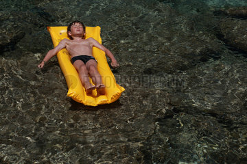 Santa Margherita di Pula  Italien  Junge liegt auf seiner Luftmatratze im Meer