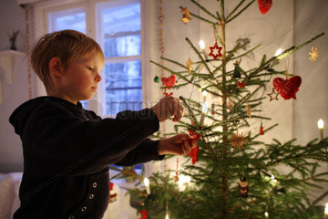 Belloe  Schweden  Junge schmueckt einen Weihnachtsbaum