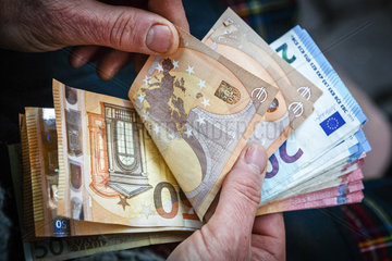 Mann zaehlt Euro Geldscheine