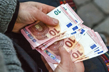 Mann haelt Euro Geldscheine in den Haenden