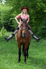 Muehlenbeck  Deutschland  Maedchen mit Cowboyhut sitzt lachend auf ihrem Pferd