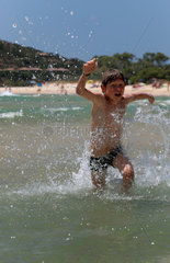 Santa Margherita di Pula  Italien  Junge rennt uebermuetig in das Meer hinein