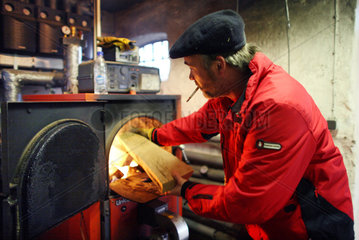 Prangendorf  Deutschland  Mann fuellt einen Holzvergaserofen mit Brennholz