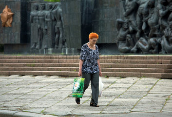 Lemberg  Ukraine  Frau mit Einkaufstueten vor dem Denkmal aus Sowjetzeiten