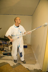 Posen  Polen  ein Handwerker streicht Waende bei der Sanierung einer Wohnung