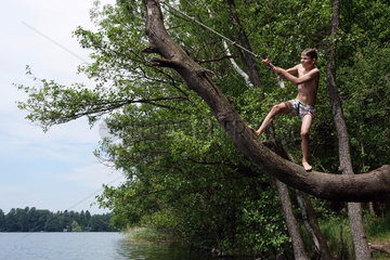 Briescht  Deutschland  Junge will von einem Baumstamm an einem Seil ins Wasser springen