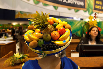 Berlin  Deutschland  Frau mit Hut voller Plastikfruechte auf der Fruit Logistica 2011