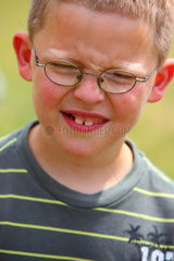 Kiel  Deutschland  kleiner Junge mit Brille und Zahnluecke verzieht sein Gesicht