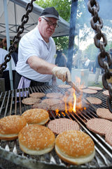 Hannover  Deutschland  Mann bereitet Hamburger auf einem Grill zu
