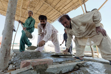 Thatta  Pakistan  Menschen giessen Bodenplatten fuer Latrinen