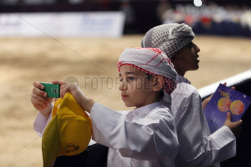 Dubai  Vereinigte Arabische Emirate  Junge in Landestracht macht ein Foto mit seinem Handy