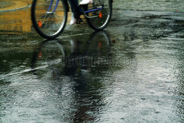 Berlin  Fahrradfahrer auf einer nassen Strasse