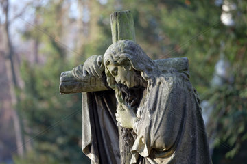 Berlin  Deutschland  trauernde Figur am Kreuz auf dem Friedhof am Suedstern