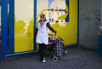 Berlin  Deutschland  eine muslimische Frau mit Kinderwagen vor einem Supermarkt