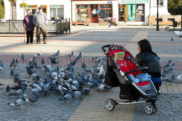 Belgard an der Persante  Polen  eine Frau fuettert Tauben auf dem Marktplatz