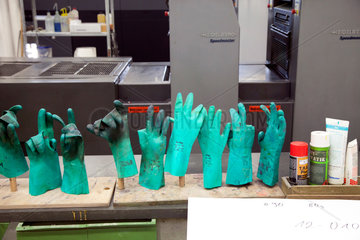 Geldern  Deutschland  gruene Gummihandschuhe in der Druckerei vor einer Heidelberger Druckmaschine