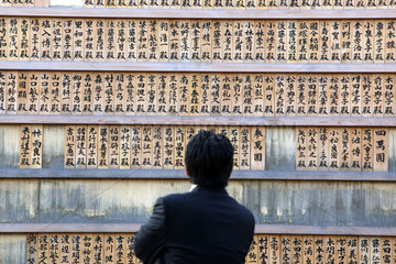 Tokio  Japan  Mann schaut sich Sotoba-Hoelzer auf dem Friedhof am Zojo-ji Tempel an