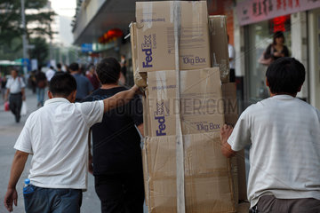 Shenzhen  China  drei Maenner schieben Pakete mit der Aufschrift FEDEX