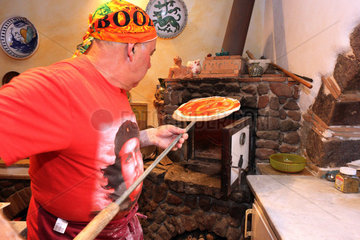 Torre Alfina  Italien  Pizzabaecker schiebt eine Pizza in einem Steinofen