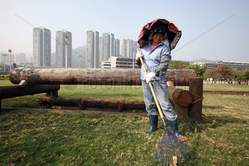 Hongkong  China  Frau harkt den Rasen auf dem Gelaende der Olympischen Reiterspiele