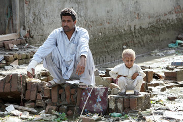 Nowshera  Pakistan  Vater und Sohn sitzen verzweifelt in einer zerstoerten Strasse