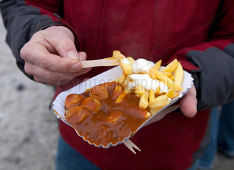 Essen  Deutschland  ein Mann isst Currywurst mit Pommes Frites und Mayo