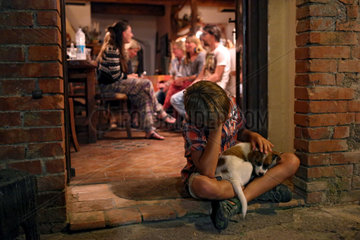 Torre Alfina  Italien  Junge sitzt traurig vor einem Haus und streichelt einen Hund
