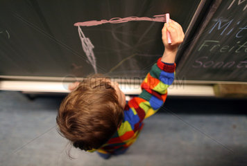 Berlin  Deutschland  Kind malt an einer Schultafel