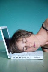 Berlin  Deutschland  Kopf einer Frau liegt erschoepft auf der Tastatur eines Laptops