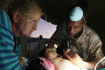 Carrefour  Haiti  eine Hebamme behandeln ein krankes Kleinkind  der Vater steht daneben