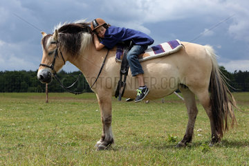 Neu Kaetwin  Deutschland  Junge schlaeft auf seinem doesenden Pferd