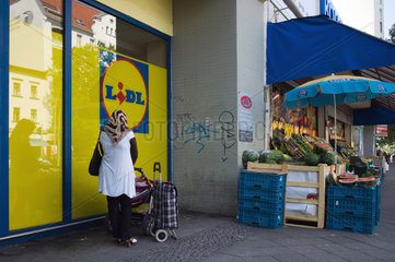 Berlin  Deutschland  eine muslimische Frau mit Kinderwagen vor einem Supermarkt