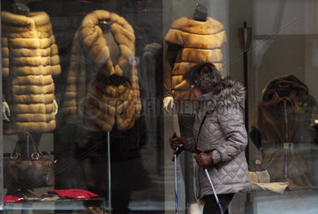 St. Moritz  Schweiz  Frau schaut sich Pelzmaentel in einem Schaufenster an