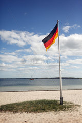 Eckernfoerde  Deutschland  Blick ueber die Eckernfoerder Bucht mit Deutschlandfahne am Strand