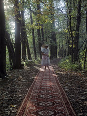 Luebben  Deutsche Demokratische Republik  Werbeaufnahme  Frau in sorbischer Tracht steht im Wald auf einem Laeufer