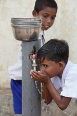 Navatkerny  Sri Lanka  ein Maedchen trinkt sauberes Trinkwasser von einer Wasserpumpe